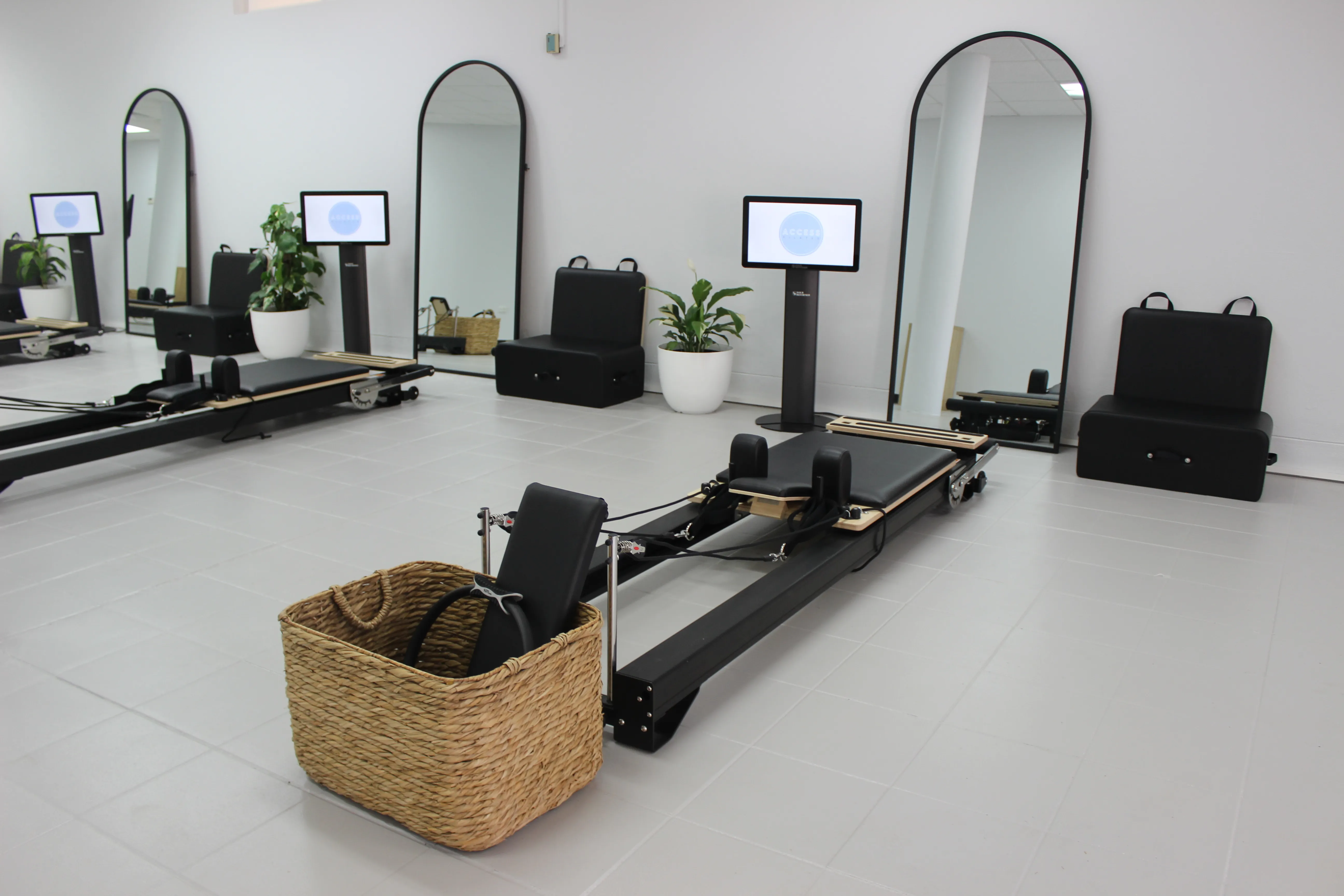 Reformers lined up in an Access Pilates studio, each with its own screen and arched mirror