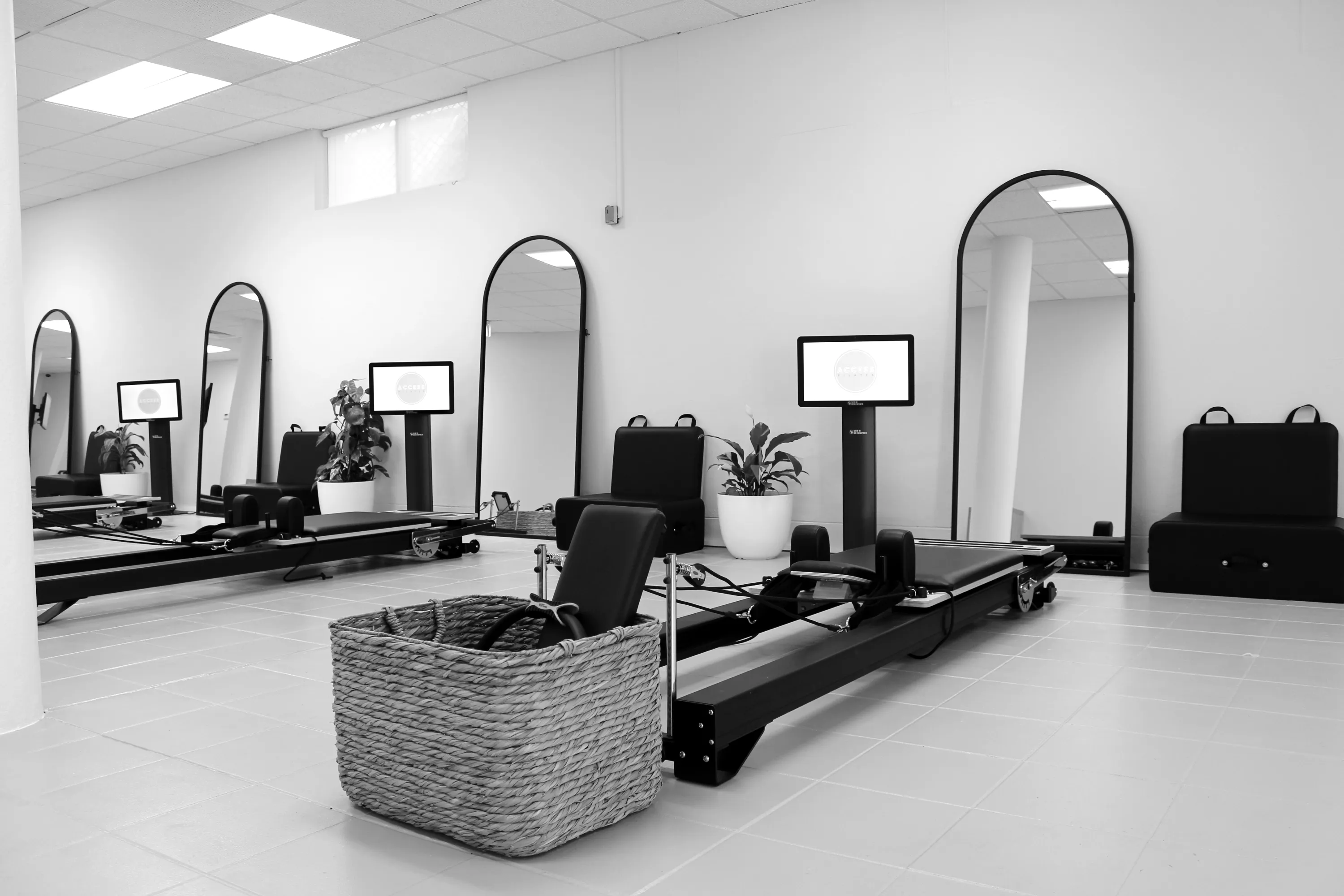 Reformers lined up in an Access Pilates studio, each with its own screen and arched mirror